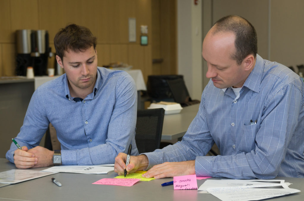 Deux hommes écrivent sur des post-its.